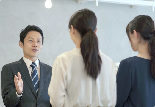 女性２人に説明する男性社員